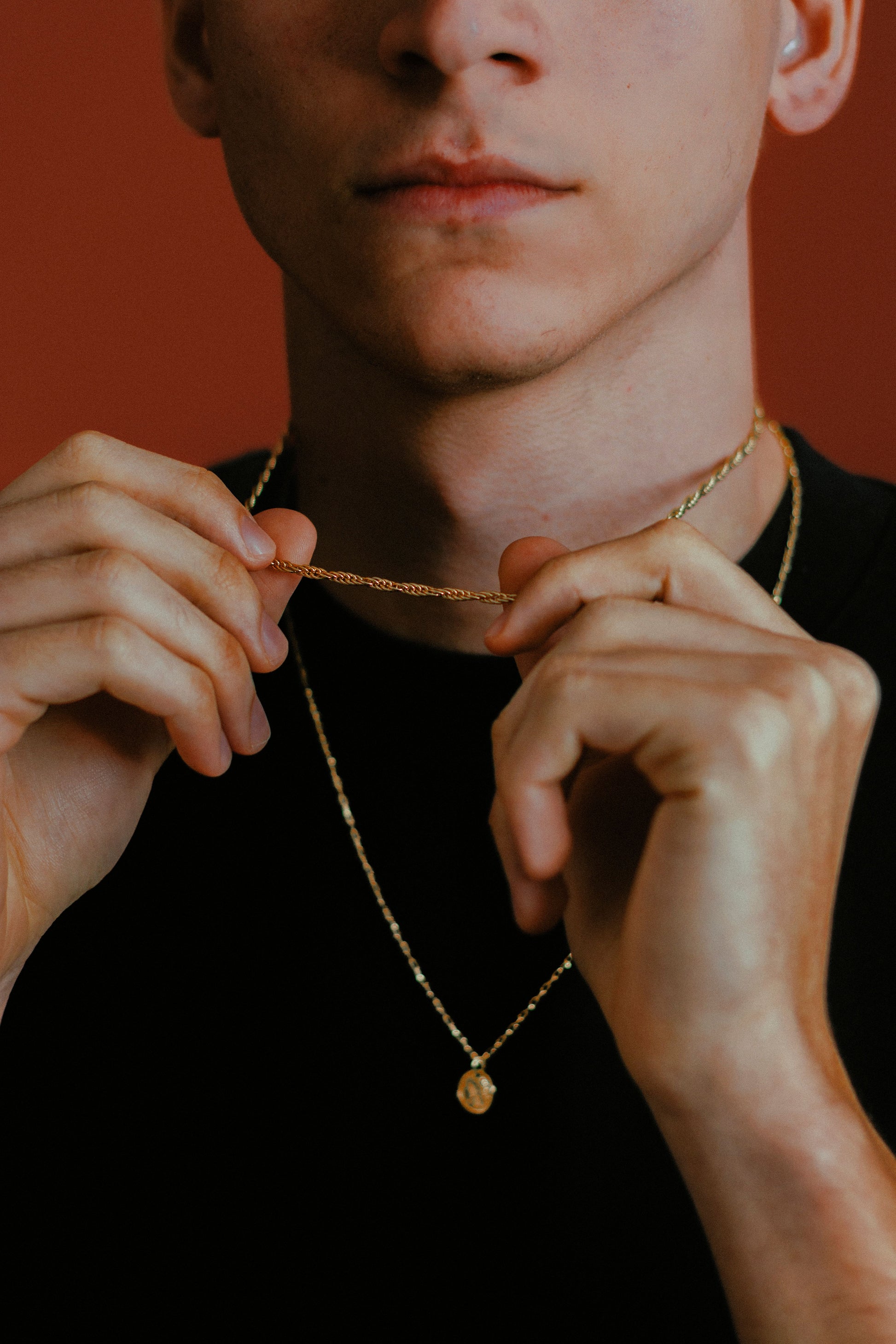 Mann legt goldene Kette mit Anhänger an – Herrenschmuck von Z Juwelier
